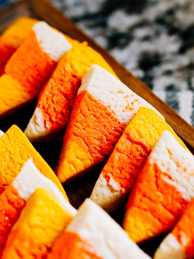 A line up of candy corn cookies on a dessert board.