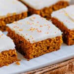A pumpkin bar frosted with cream cheese icing on a serving plater.