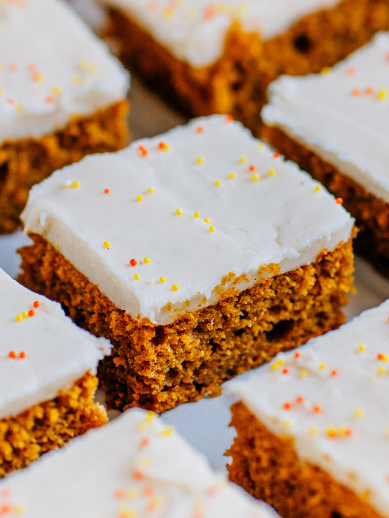 Row of perfectly made frosted pumpkin bars ready to be served.