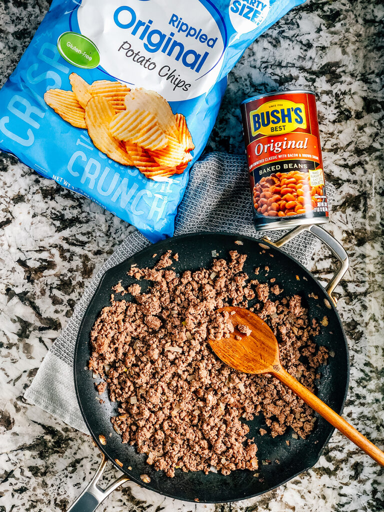 The three ingredients that make this simple meal of ground beef and beans: Browned ground beef, a large can of bush's baked beans, and ripple chips.