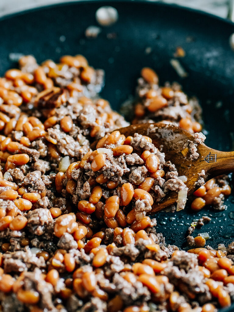 Close up of baked beans and ground beef in a skillet.