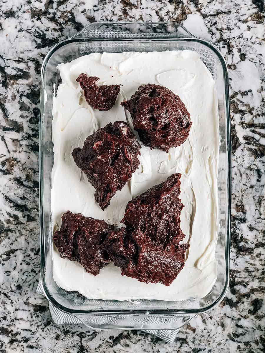 Cuilères de pudding au chocolat sur la couche de fromage à la crème fouettée.