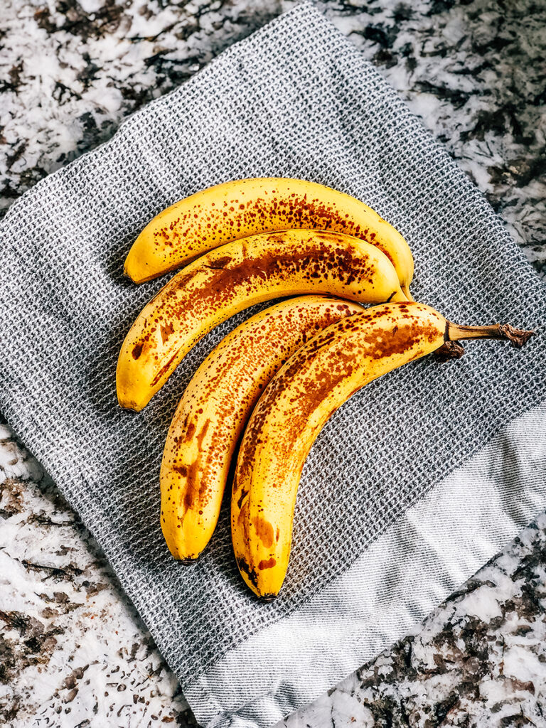 Four overly ripe bananas on a kitchen towel.