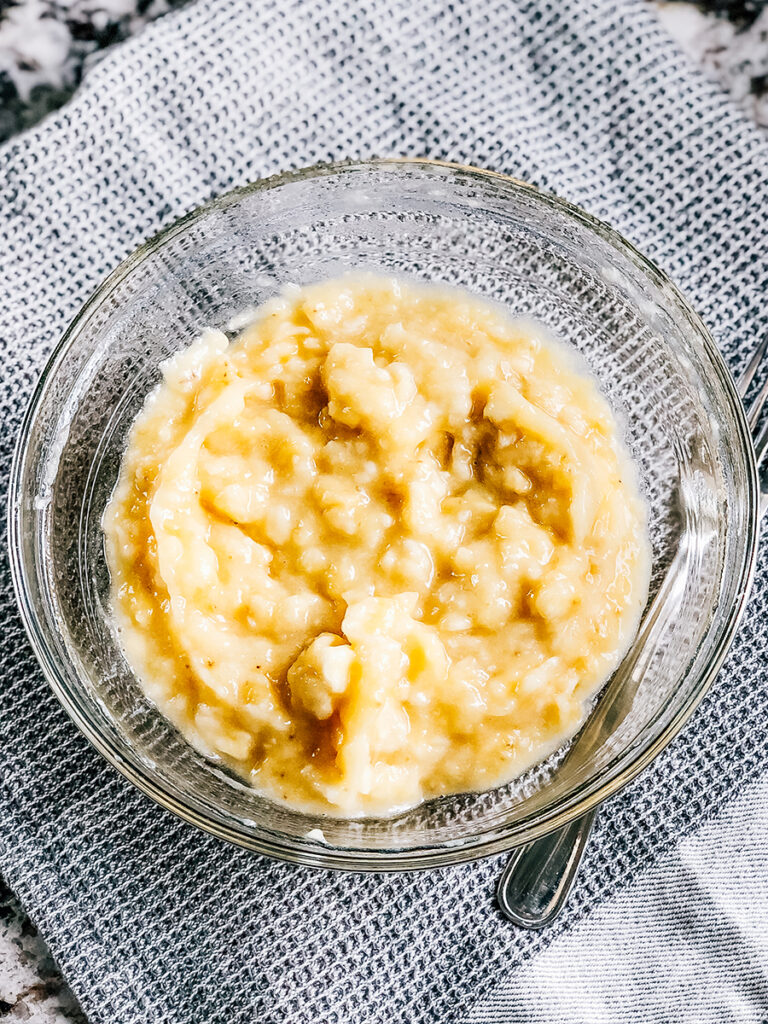 Four mashed bananas in a glass bowl.
