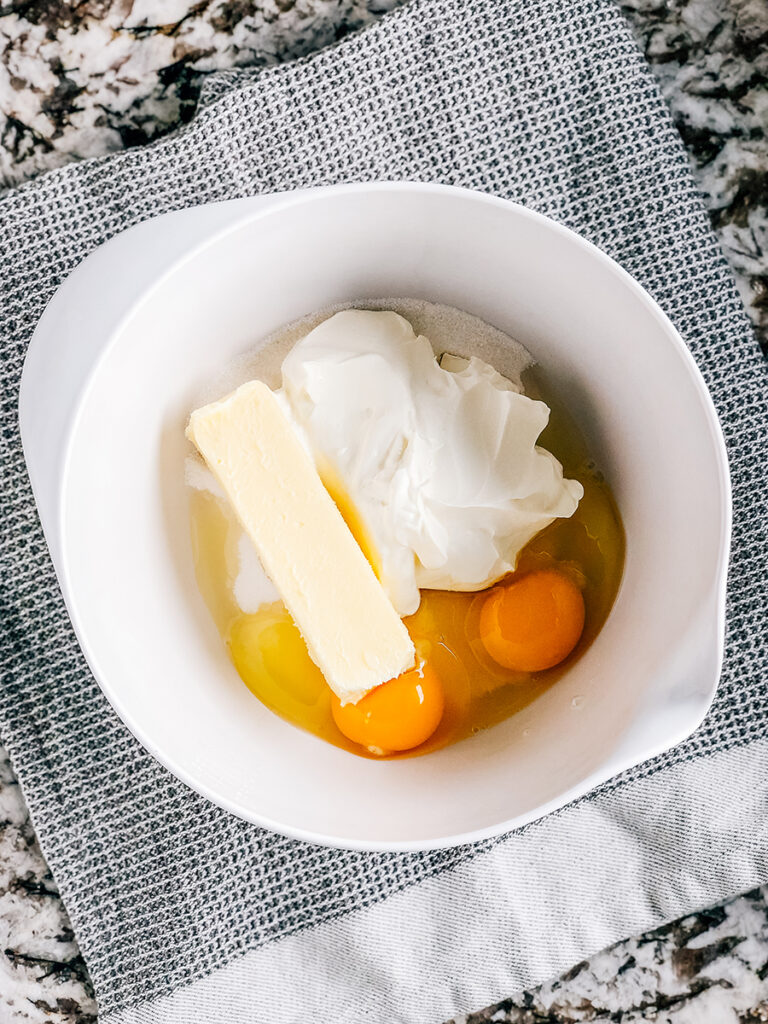 Sugar, sour cream, softened butter, and eggs in a mixing bowl.