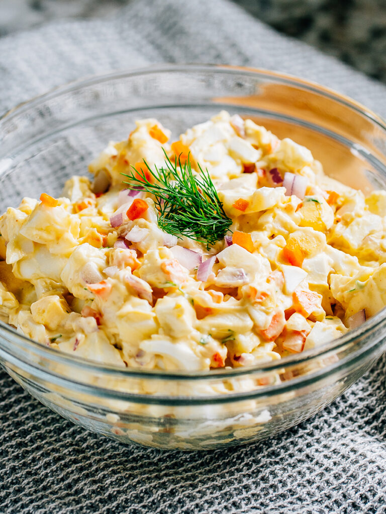 Competed mix egg salad ready in a clear glass bowl.
