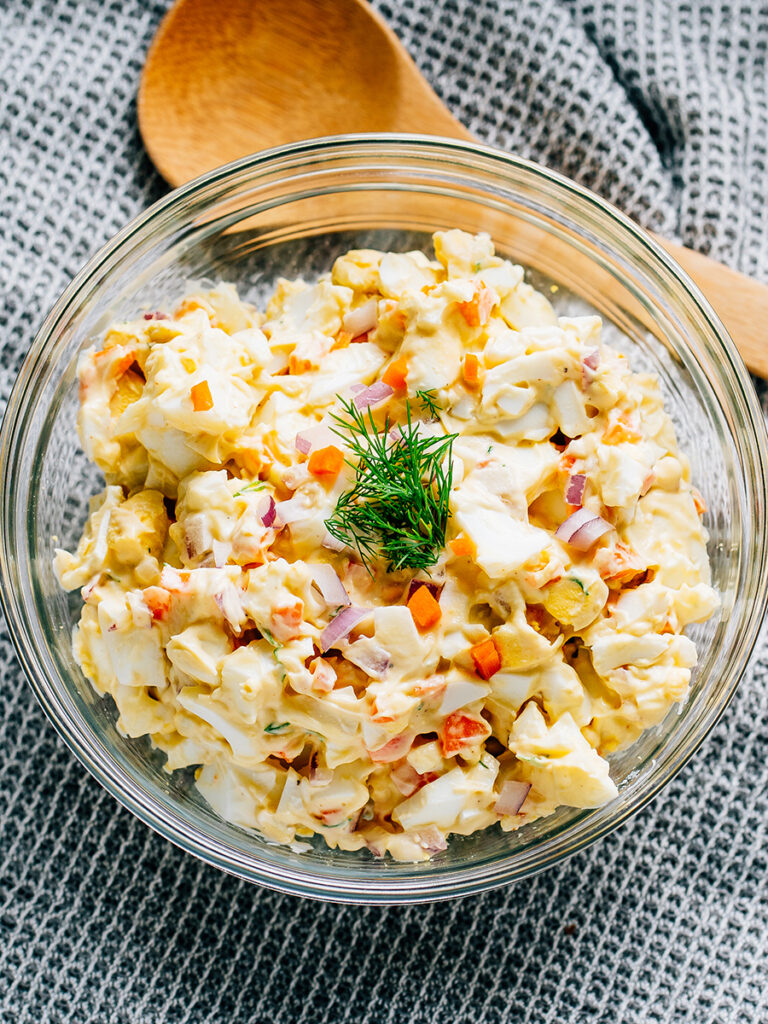 Egg salad with miracle whip and dijon mustard in a glass bowl.