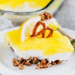 Tart lemon pie filling spread on a sweet and creamy cream cheese and Cool Whip layer and buttery pretzel crumb crust is this lemon pretzel dessert plated and ready to be enjoyed!