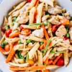 Overview of plated chicken primavera that full of spring veggies, penne pasta, and fried chicken breasts.