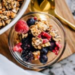 Overview of a small bowl of homemade granola mixed with frozen fruit ready to be served.
