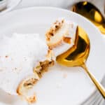 Layers of a simple graham cracker crumb crust, cheesecake, pumpkin pie filling, and Cool Whip topping is this fun fall dessert No-Bake Pumpkin Cheesecake Delight shown on a spoon.