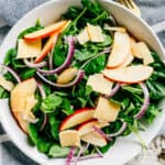 Completed salad. Thinly sliced apples and red onions with shaved Parmesan and chopped walnuts over a bed of spinach and arugula drizzled in a homemade dressing made of oil, lemon, honey, salt and pepper.