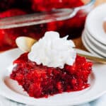 Cranberry jello with crushed pineapple, whole berry cranberry sauce, and raspberry jello completely set and garnished a dollop of Reddi Whip!