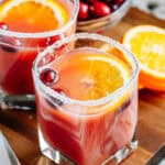 A single glass of orange cranberry punch with pineapple juice and ginger ale in a sugar rimmed glass.