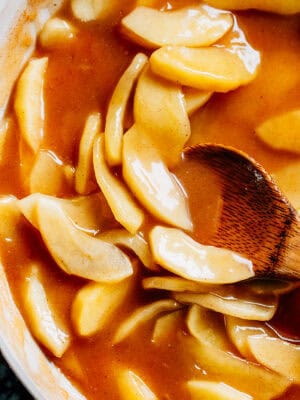 Tender apple slices coated in cinnamon sugar glaze in a large skillet.