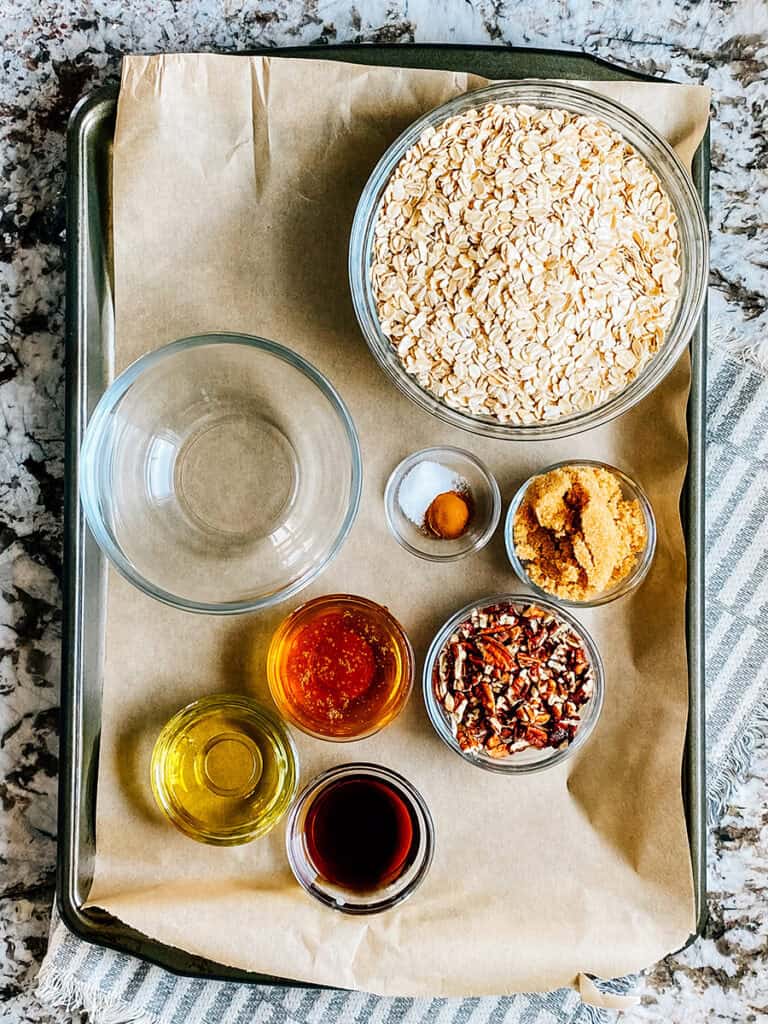 The ingredients for homemade cinnamon sugar granola: Oats, brown sugar, salt, cinnamon, chopped nuts, honey, oil, and vanilla.