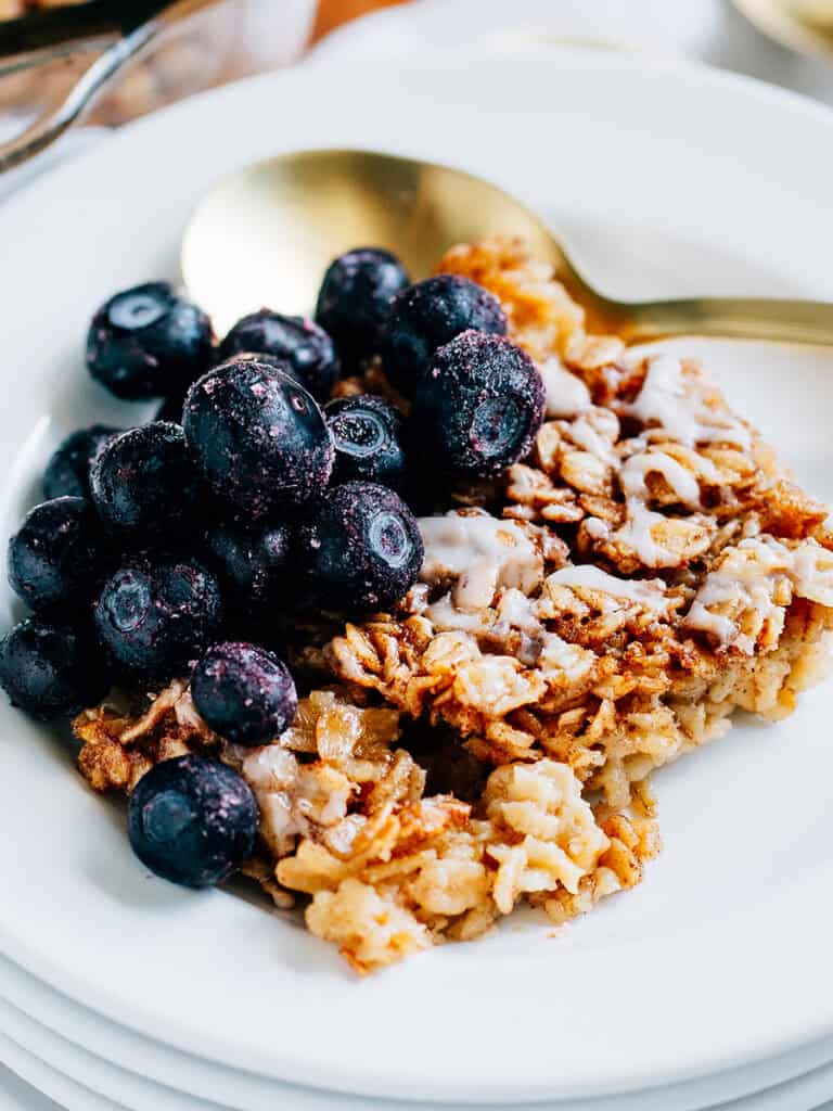 Overview: Softened hearty oats covered in sweet cinnamon sugar drizzled with a simple glaze and topped with frozen blueberries plated and ready to eat.