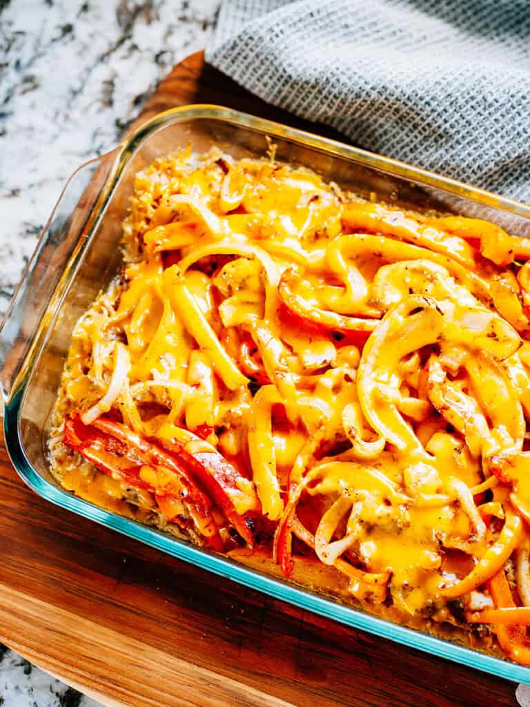 Melted cheddar cheese on top of baked chicken, peppers, and onions seasoned with a fajita spices.