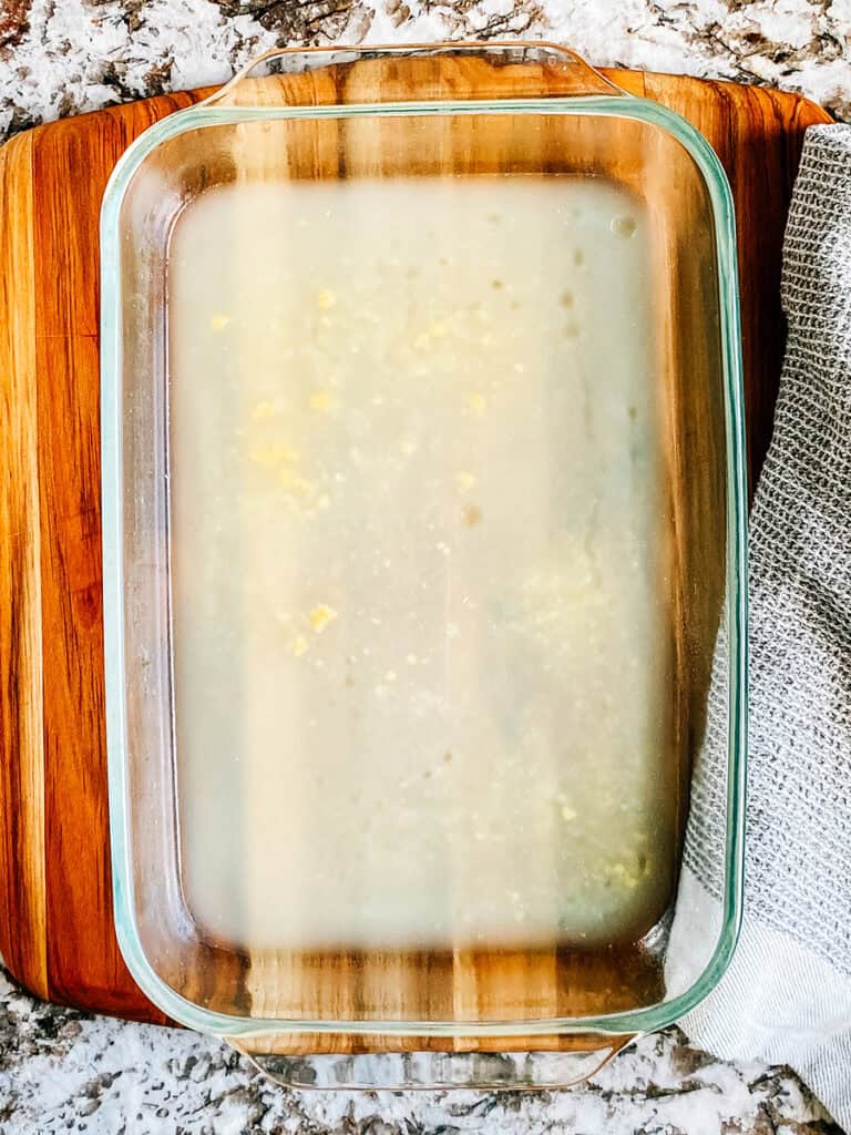 A 9x13 in baking dish with chicken broth on the bottom.