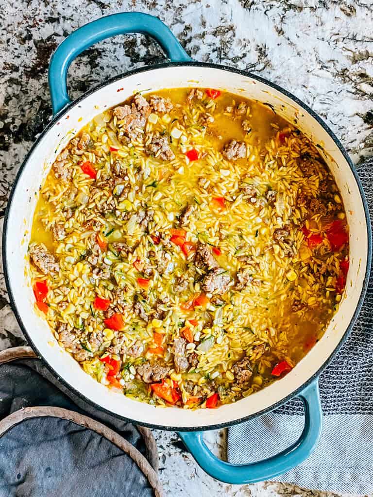 The sausage, orzo, broth, and vegetables mixed and all the orzo below the broth.