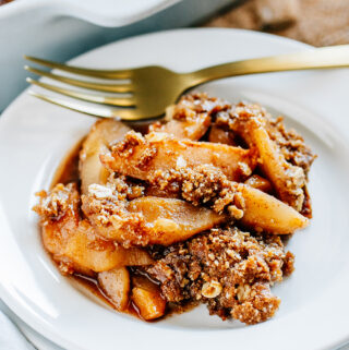 Tender cinnamon sugar apples with a buttery brown sugar and oat crumble, this apple crisp is plated and ready to be enjoyed.