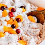 A bowl showing the inside mix of finely chopped cranberries and oranges with the garnish of whole cranberries and slices of canned oranges.