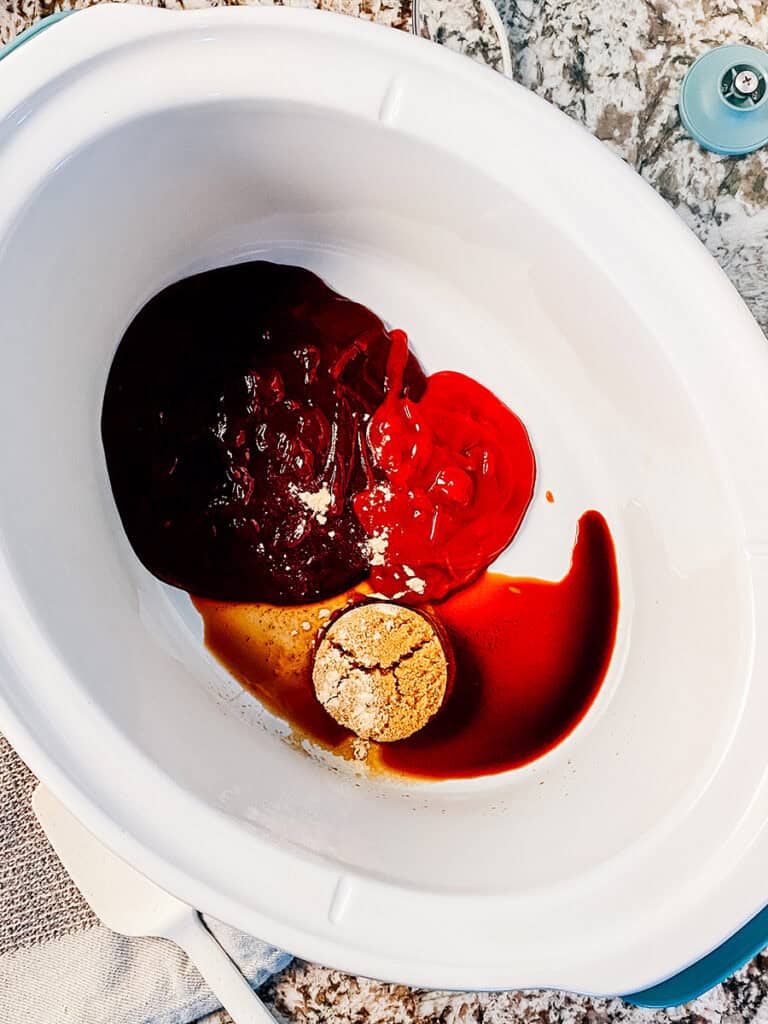 The bbq sauce ingredients in the slow cooker: bbq sauce, ketchup, brown sugar, garlic powder, and Worcestershire sauce.