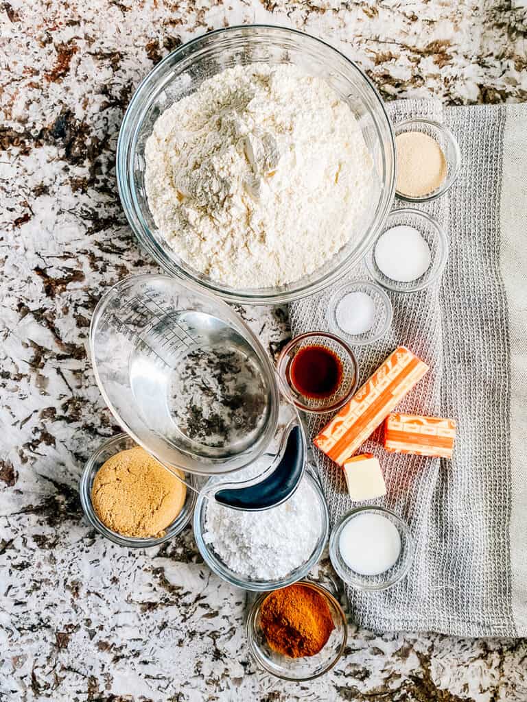The ingredients to easy Cinnamon Focaccia Bread: Flour, sugar, yeast, water, butter, cinnamon, brown sugar, powdered sugar, vanilla extract, and milk.