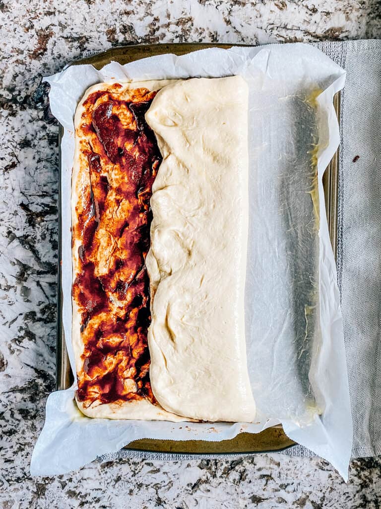 Folding the focaccia bread to create layers of swirling cinnamon sugar.