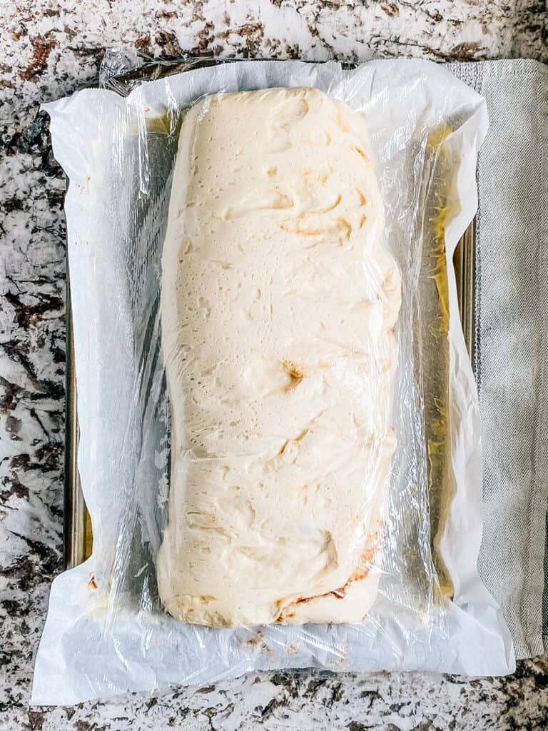The focaccia bread covered in plastic wrap and risen for 45 mins.