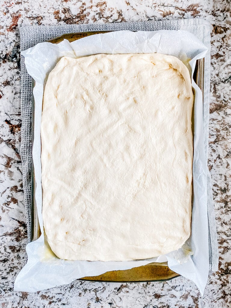 The focaccia bread stretched out to fit the sheet pan.