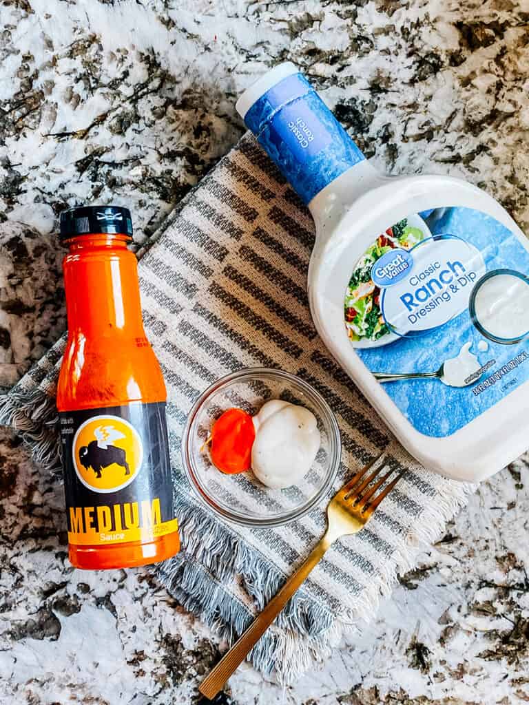 The ingredients to the simple buffalo dressing in this chicken salad: Medium wing sauce and Ranch dressing on the counter.