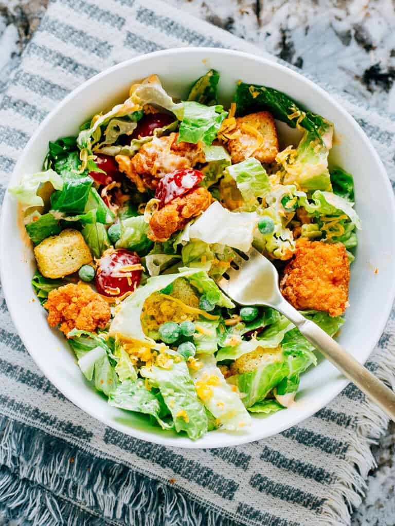 A forkful of lettuce, cherry tomato, and chicken from this supper yummy buffalo chicken salad.