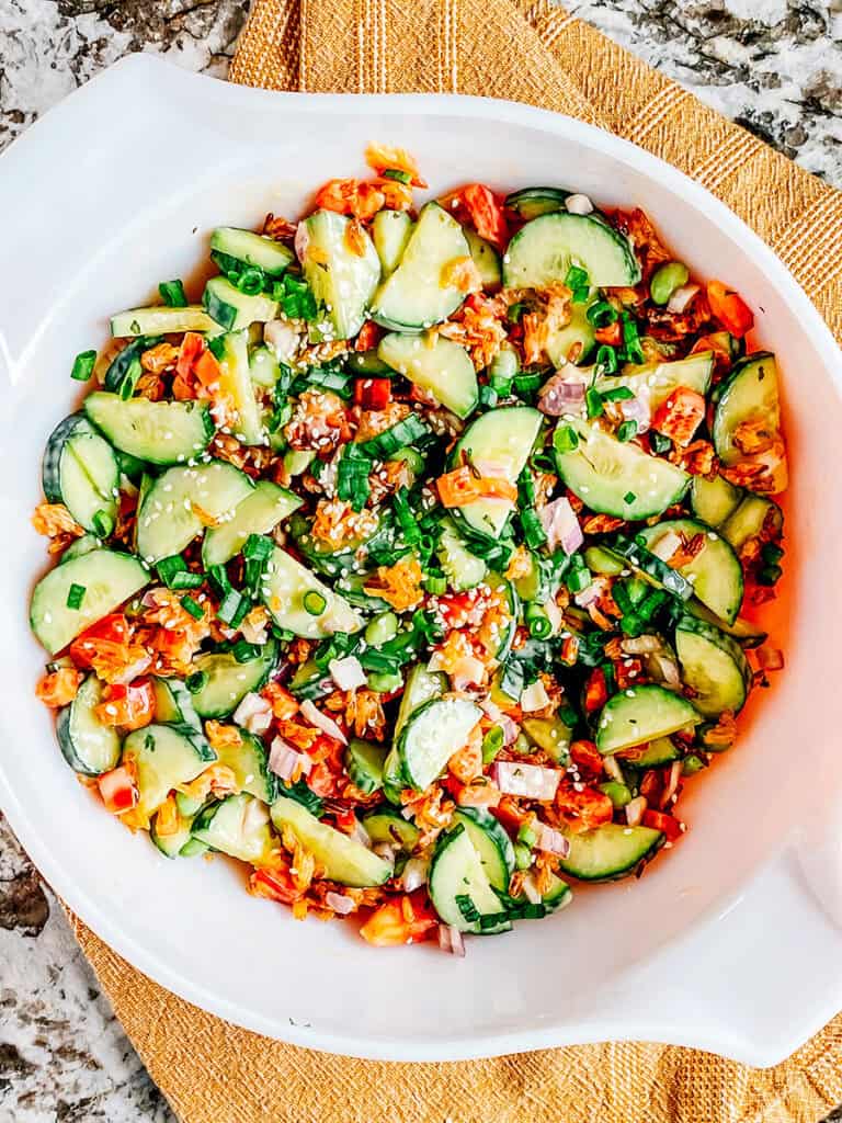 A completely mixed crispy rice and cucumber salad with spicy mayo dressing and green onion and sesame seed toppings ready to serve to guests.