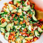 A completely mixed crispy rice and cucumber salad with spicy mayo dressing and green onion and sesame seed toppings ready to serve to guests.