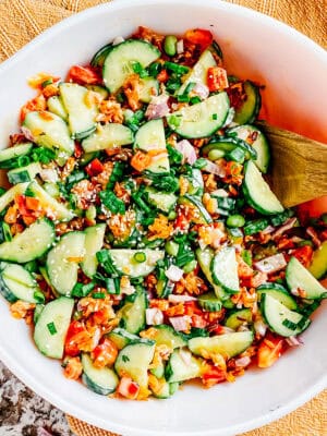 A completely mixed crispy rice and cucumber salad with spicy mayo dressing and green onion and sesame seed toppings ready to serve to guests.