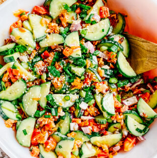A completely mixed crispy rice and cucumber salad with spicy mayo dressing and green onion and sesame seed toppings ready to serve to guests.