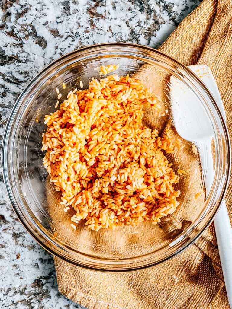 Mix and evenly coated rice in a medium bowl ready to be place on a baking sheet.