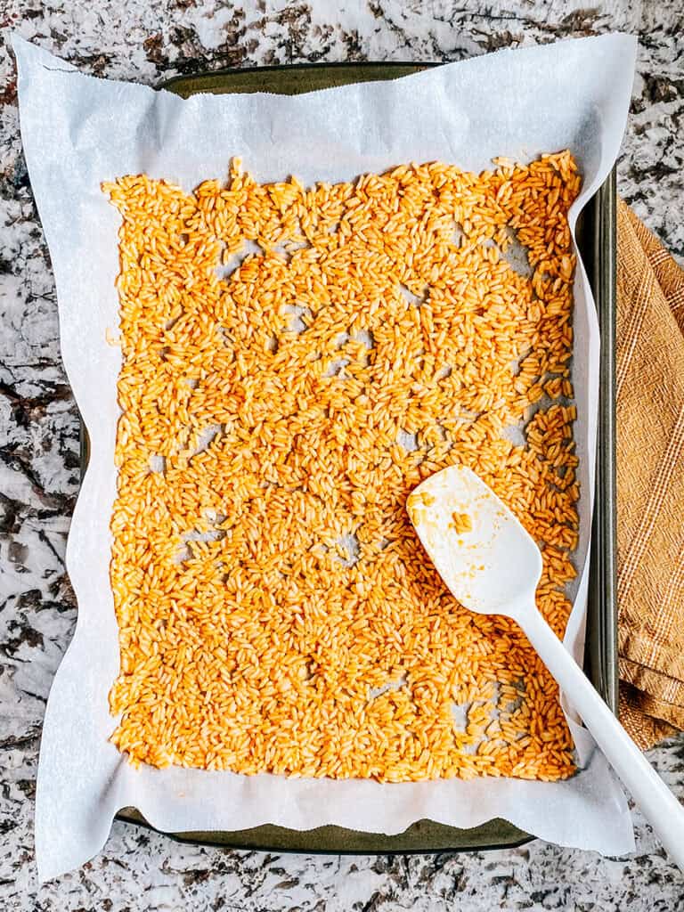 The prepared rice on a rimmed baking sheet lined with parchment paper.