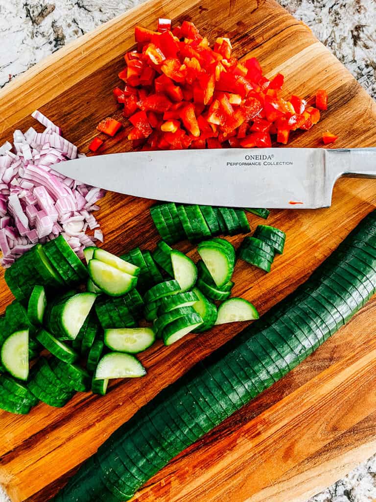 Prepared vegetables for crispy rice salad: sliced cucumbers, diced red peppers, finely diced red onion, and prepared avocado(optional and not pictured.)