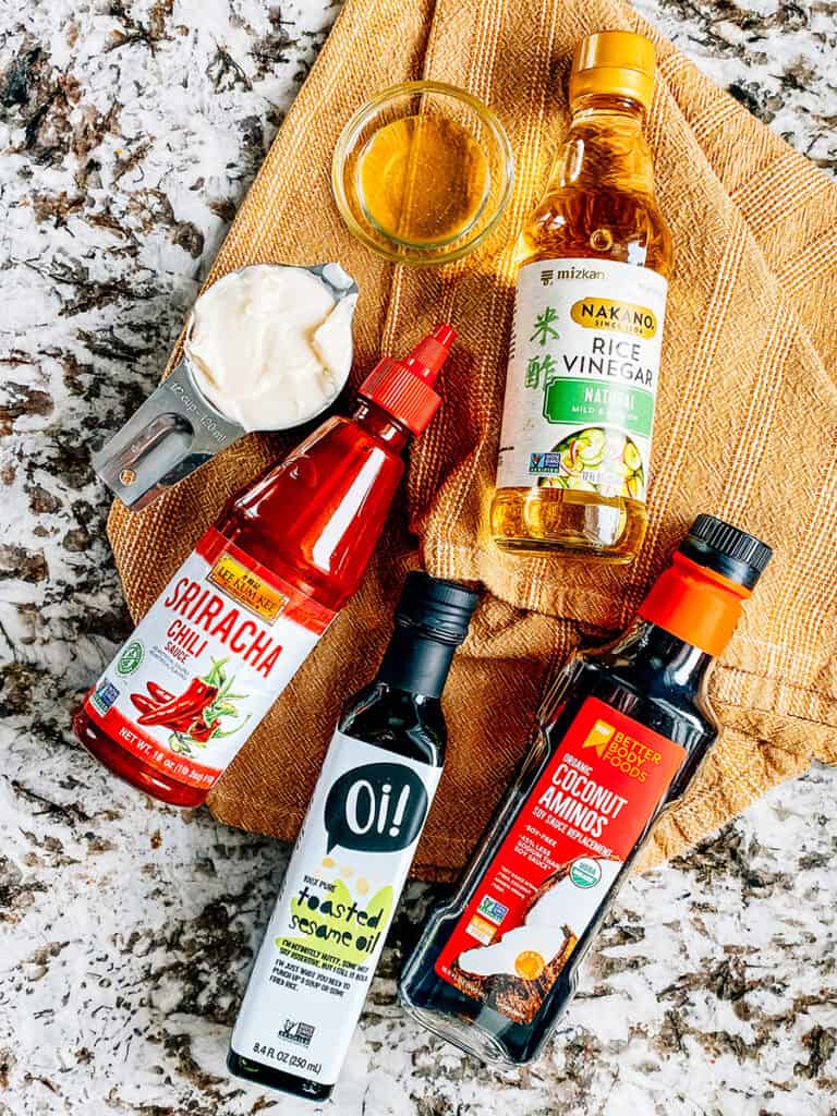 The ingredients for the homemade spicy dressing of the crispy rice salad recipe: Mayo, white vinegar, rice vinegar, soy sauce, sesame oil, and sriracha sauce.