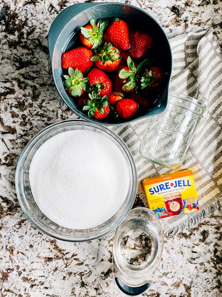 Ingredients to homemade strawberry freezer jam: fresh strawberries, sugar, water, and Sure-Jell.