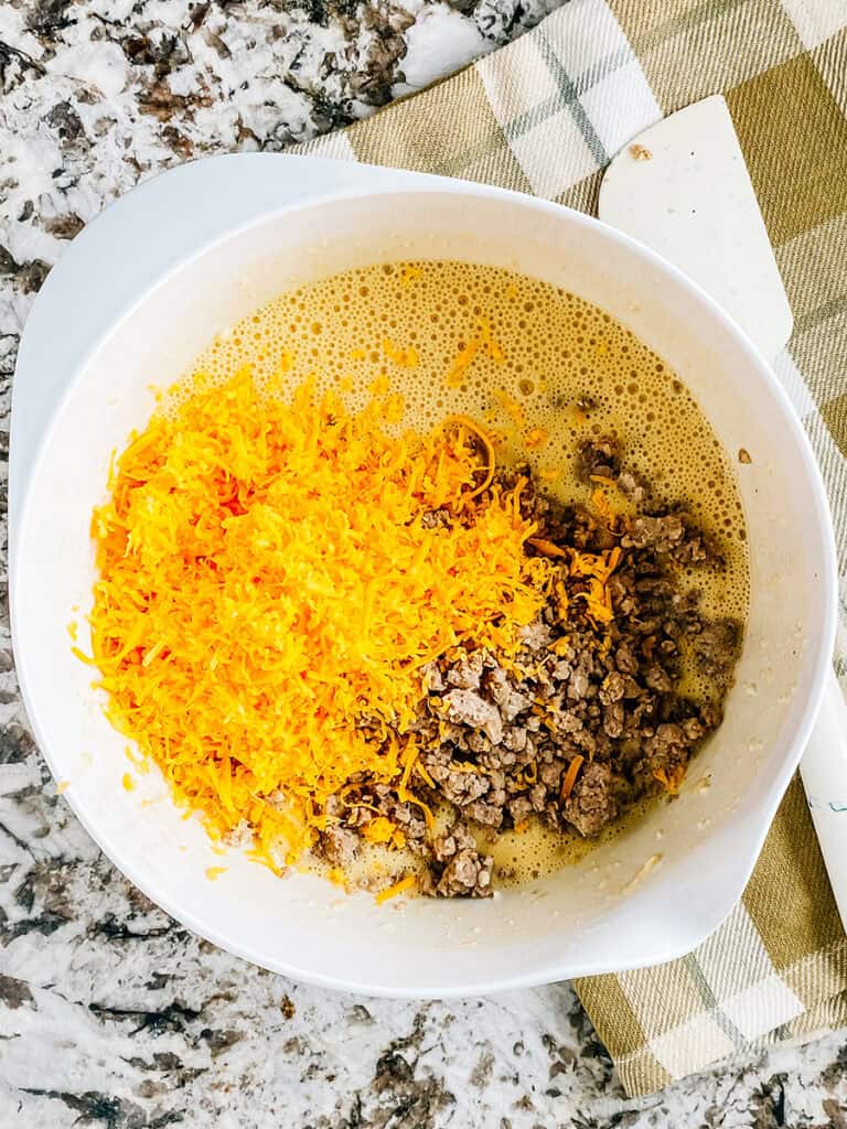 Sausage and cheese added to the mixing bowl of pancake mix.