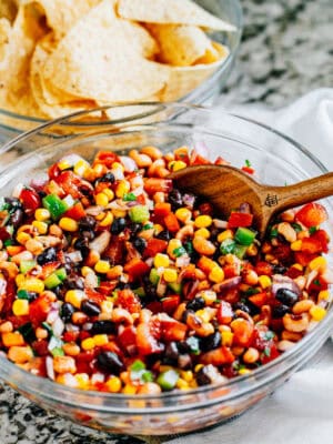 The serving bowl of cowboy caviar with a bowl of tortilla chips in the background.