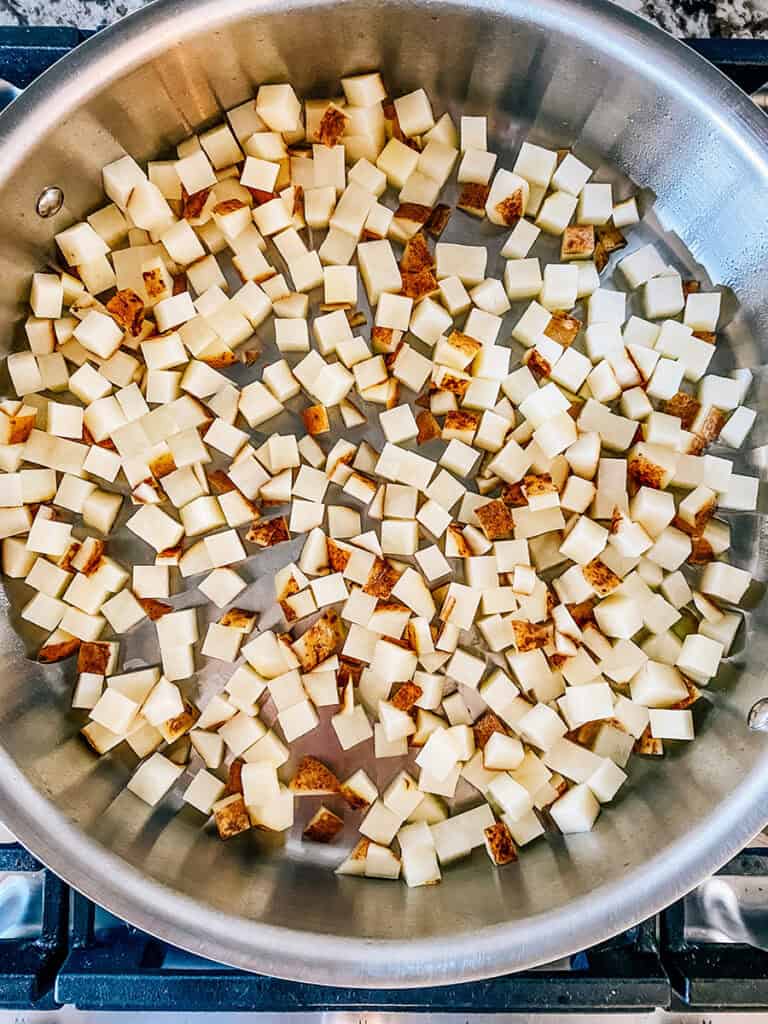 Two pounds of diced potatoes in a hot, oiled stainless steel skillet.