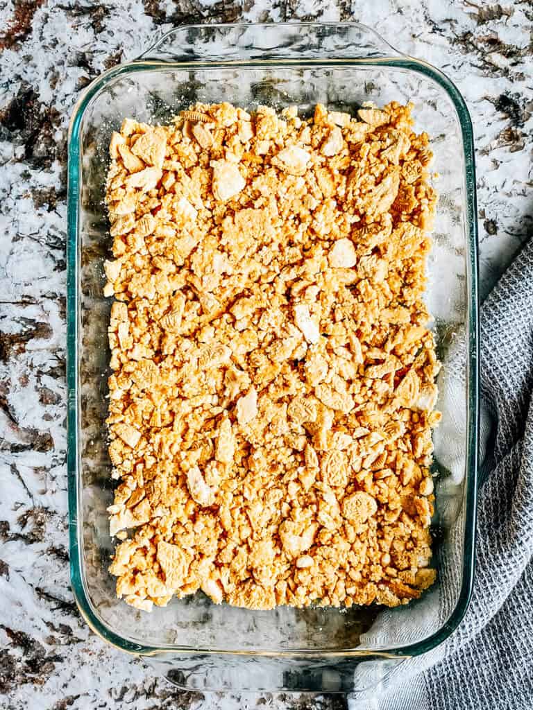 A crumbled cookie crust pressed into the bottom of a 9x13-inch dish.