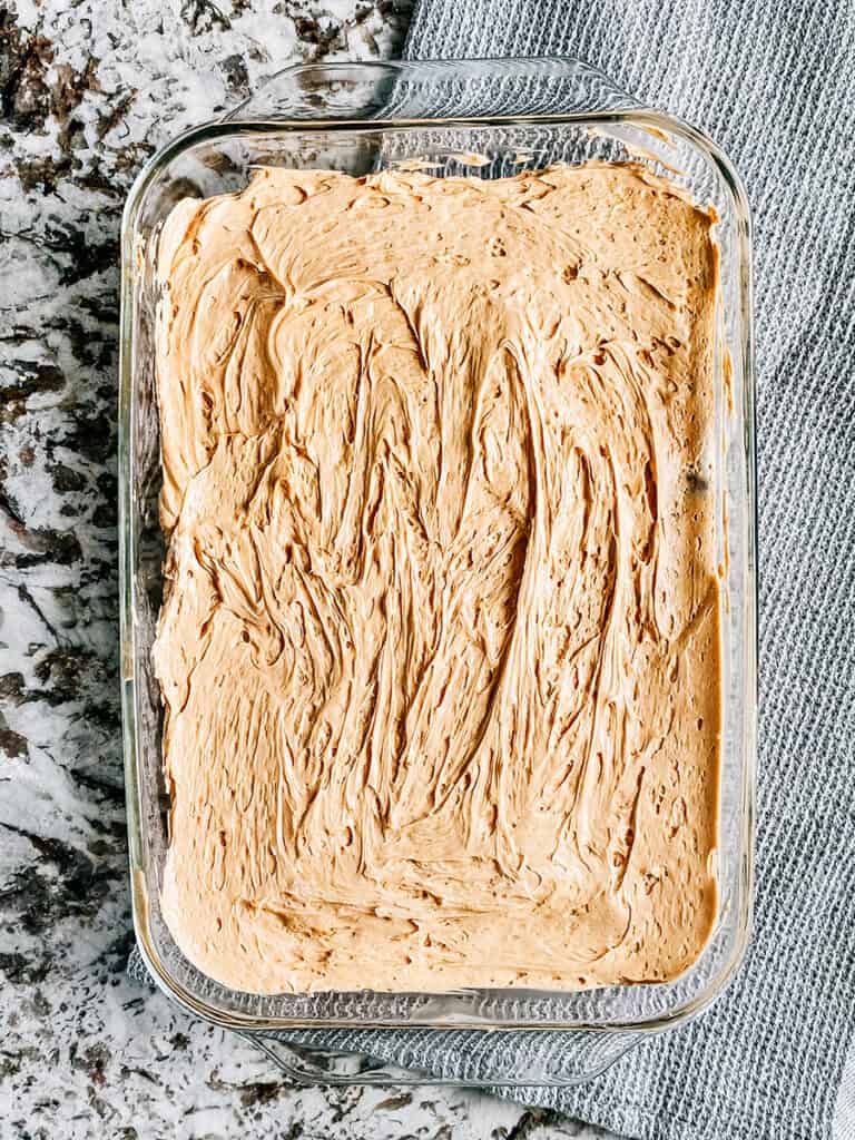 An even layer of whipped topping with peanut butter and hot fudge in it on the ice cream sandwiches.