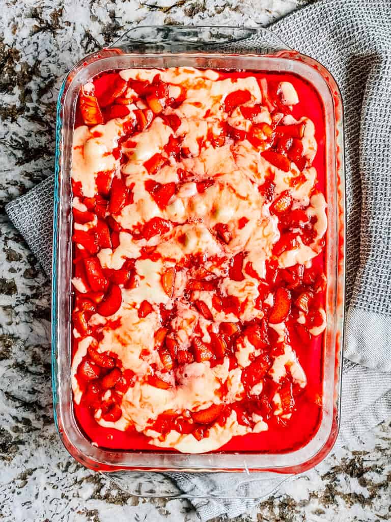 The cooked rhubarb and strawberry jello syrup pour over the cake batter and mini marshmallows.