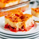 A fun strawberry jello rhubarb cake plated with a forkful missing.