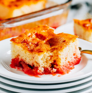 A fun strawberry jello rhubarb cake plated with a forkful missing.